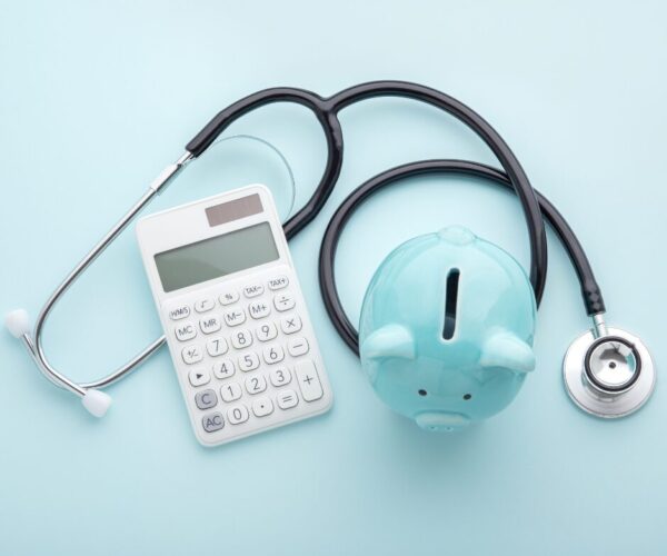 calculator and stethoscope with piggy bank
